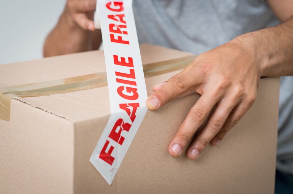 man marking a box with fragile sign