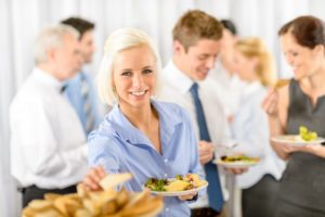 Smiling business woman during company lunch buffet hold salad plate