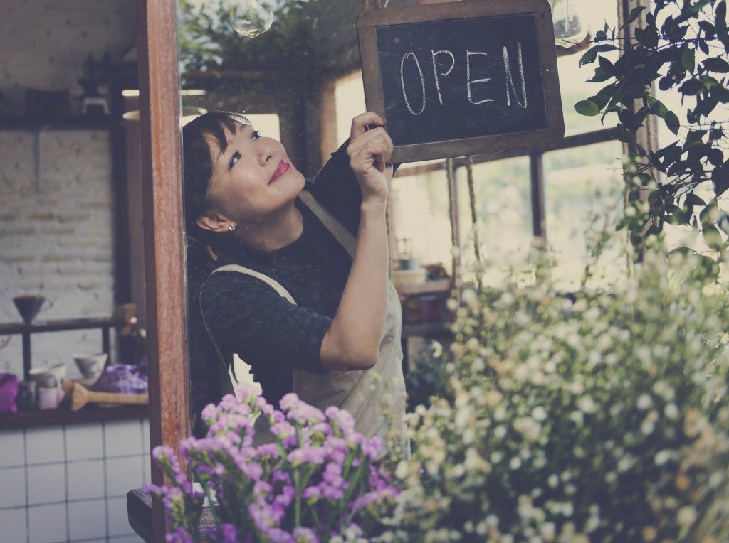 Female placing "open" sign in front of store